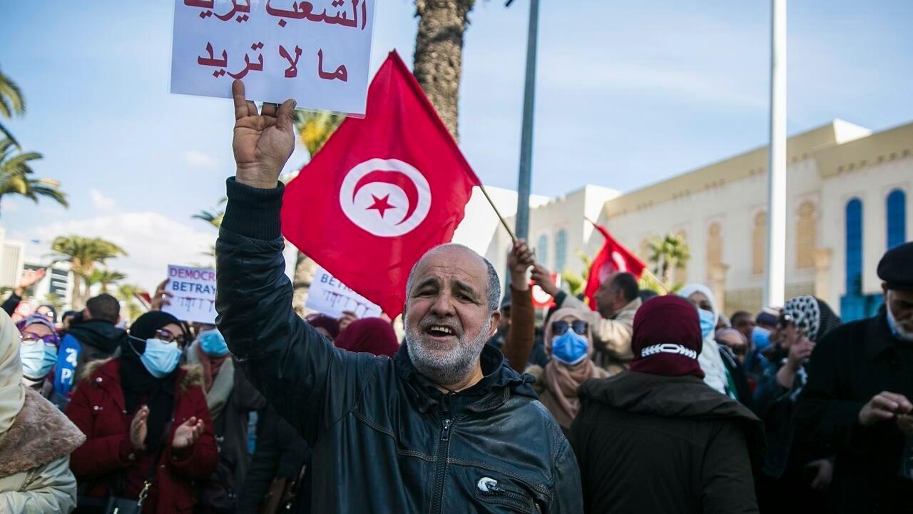 A demonstrator holds a placard with a text written in Arabic reading, « The people want what you don&rsquo;t want », during a protest against Tunisian President Kais Saied in Tunis, Tunisia, Sunday, Feb. 13, 2022. (AP Photo/Hassene Dridi)