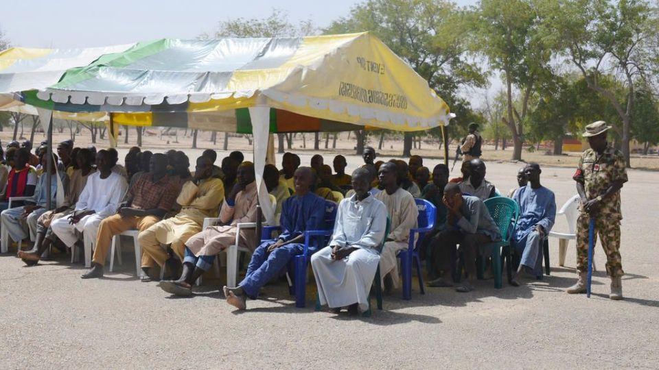 FILE- In this Feb. 12, 2016, file photo, men who were detained by Nigeria army who have no links to Boko Haram sit under a canopy before their release at the Giwa military barracks in Maiduguri, Nigeria. Babies and children are among scores of people dying in military detention at the notorious Nigerian Giwa military barracks where soldiers illegally hold suspected Islamic extremists, Amnesty International charged Wednesday, May 11, 2016. (AP Photo/Jossy Ola, File)