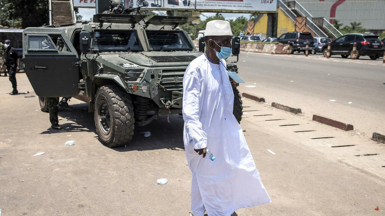 A man walks in-front of a armoured military vehicle after the first session of talks between Colonel Mamady Doumbouya and current Guinean political parties in Conakry on September 14, 2021. – Colonel Mamady Doumbouyas special forces on September 5, 2021 seized Alpha Conde in a Coup, the West African state’s 83-year-old president, a former champion of democracy accused of taking the path of authoritarianism. (Photo by JOHN WESSELS / AFP)
