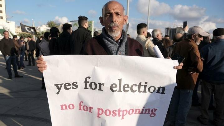 A man holds a banner during a protest against the delay to the Libyan presidential election initially planned for December 24, in Benghazi, Libya December 24, 2021. REUTERS/Esam Omran Al-Fetori