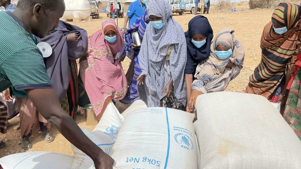 People receive bags of relief grains at a camp for the Internally Displaced People in Adadle district in the Somali region, Ethiopia, January 22, 2022. Picture taken January 22, 2022. Claire Nevill/World Food Programme/Handout via REUTERS THIS IMAGE HAS BEEN SUPPLIED BY A THIRD PARTY. MANDATORY CREDIT.