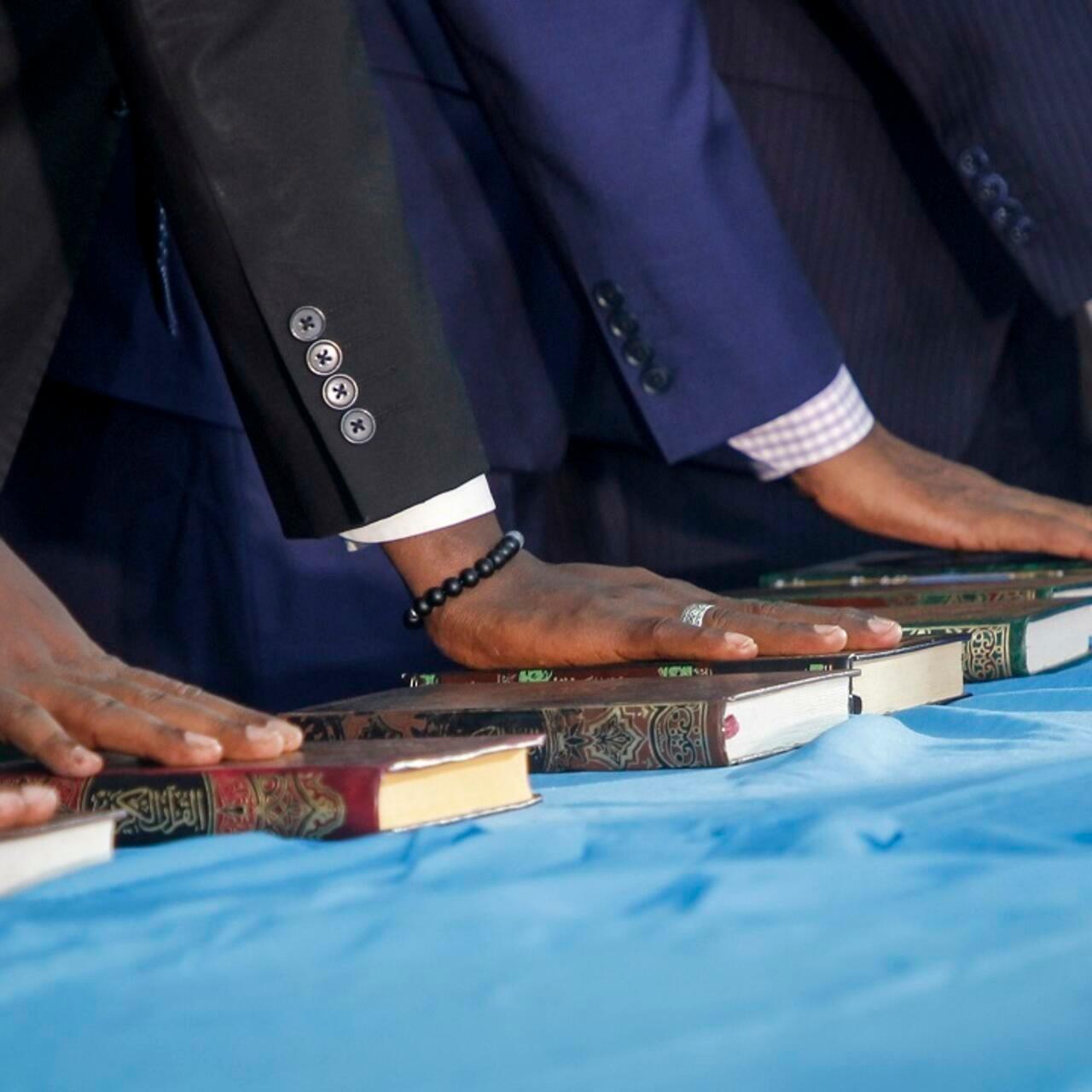 Somali lawmakers are sworn-in to office, with their hands on Qurans, at a ceremony held in the capital’s heavily fortified Halane military camp, in Mogadishu, Somalia Thursday, April 14, 2022. Somalia on Thursday inaugurated 290 new lawmakers, bringing the country a step closer to completing a prolonged electoral process marred by alleged corruption and irregularities. (AP Photo/Farah Abdi Warsameh)