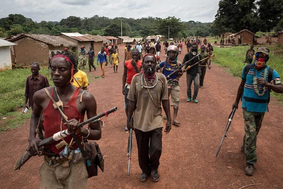 Antibalaka fighters walk in Gambo, southeast Central African Republic, on August 16, 2017. Antibalaka fighters fought against a Seleka militia to chase them out of Gambo in early August. They say that they are now hundreds in town, with most of the civilians have fled to escape the battles. / AFP PHOTO / ALEXIS HUGUET