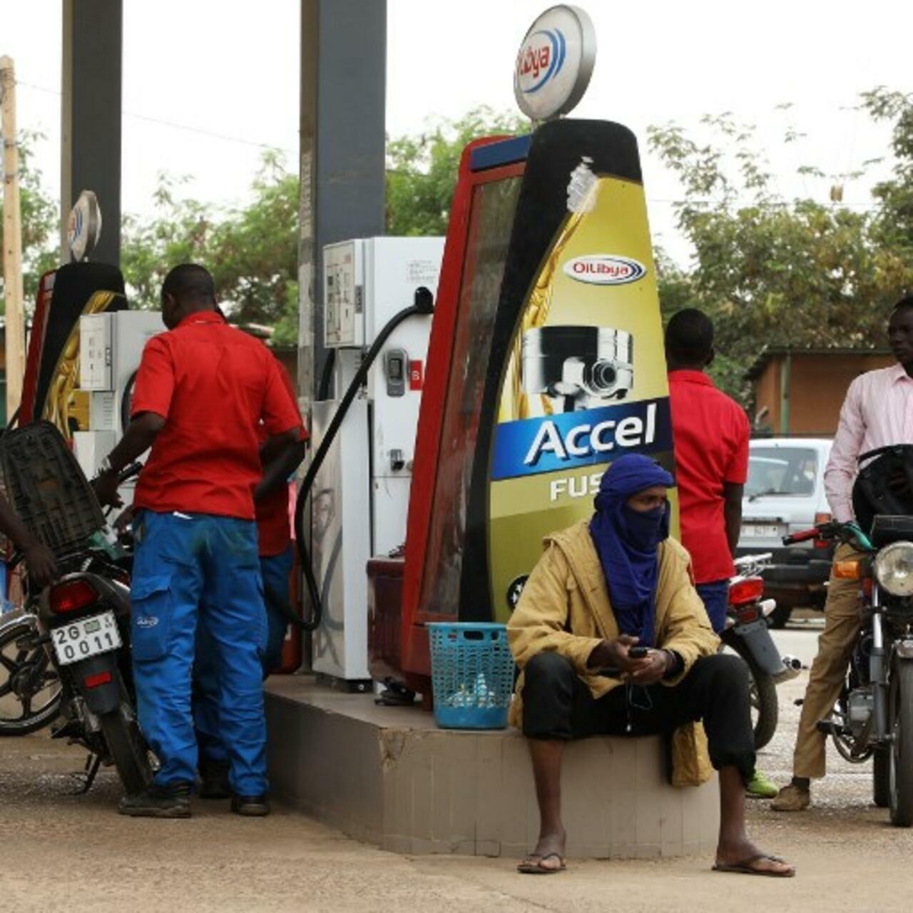 Men fuel motorbikes at a petrol station on December 21, 2017, in Niamey. (Photo by LUDOVIC MARIN / AFP)