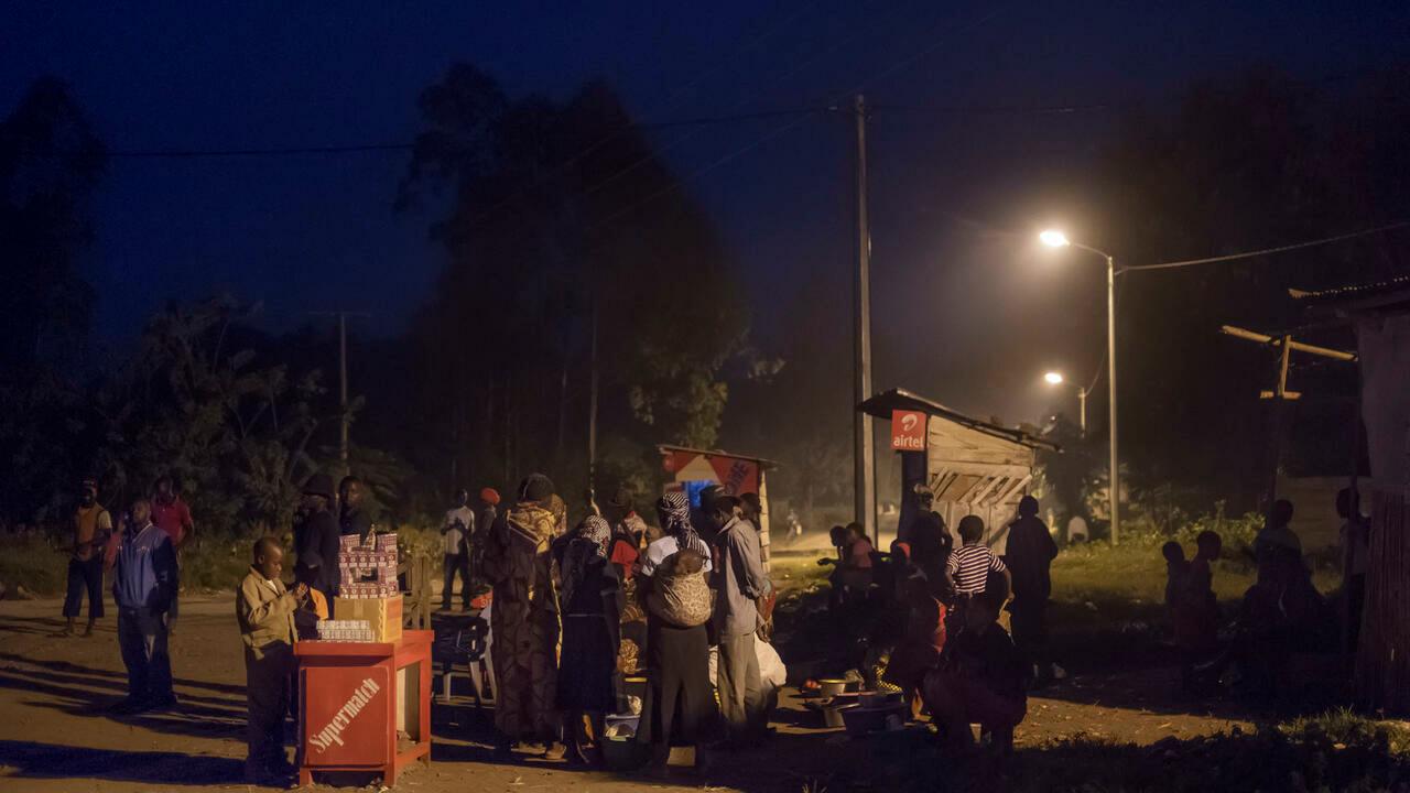 People gather around commerce stalls in the streets enlightened by electric lightning in Bugara on July 17, 2016. – The vast majority of the Congolese population doesn’t have access to electricity, and the small portion of the inhabitants that are connected to the grid are suffering frequent and long breakdowns. In the case of the village of Bugara, electricity is produced by the dam of Matebe, a project from the Virunga Alliance for a sustainable development in the surroundings of the Virunga National Park. (Photo by Eduardo Soteras / AFP)