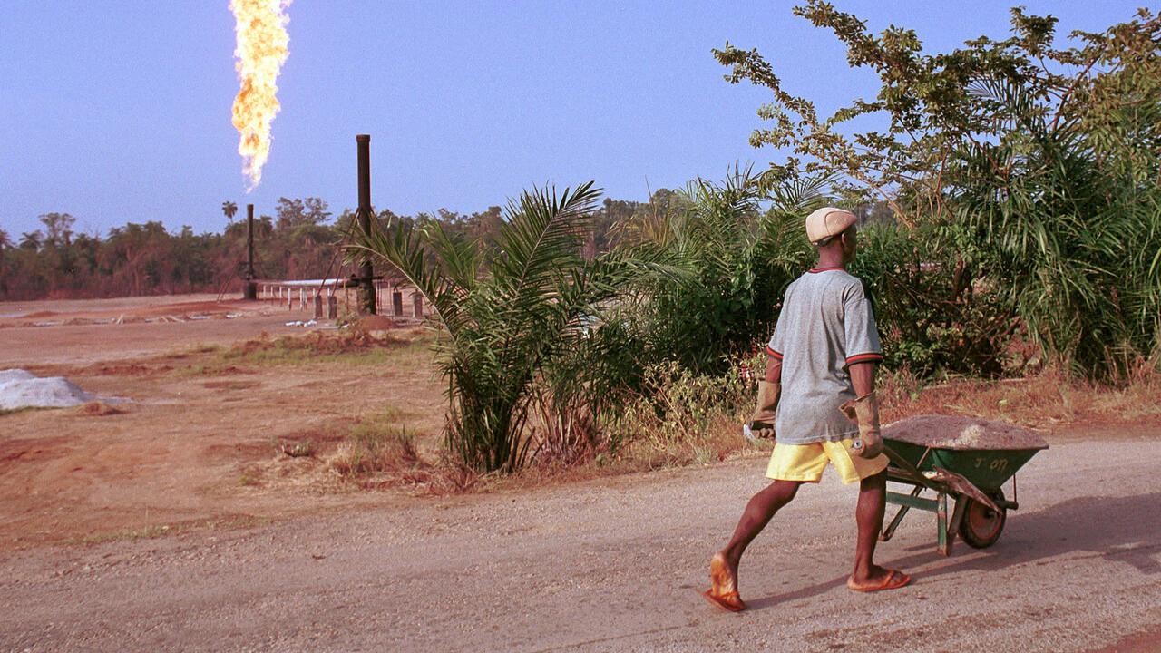 390464 36: A villager walks past a column of fire from the Oshie flare station owned by Italian oil company Agip, March 8, 2001 near Akaraolu, Nigeria. The natural gas flare was lit in 1972 and has been on continuously ever since. Human Rights Watch estimates that Nigerian gas flares release 35 million tons of carbon dioxide and 12 millions tons of methane into the atmosphere each year. Flaring is a by-product of oil drilling. (Photo by Chris Hondros/Getty Images)
