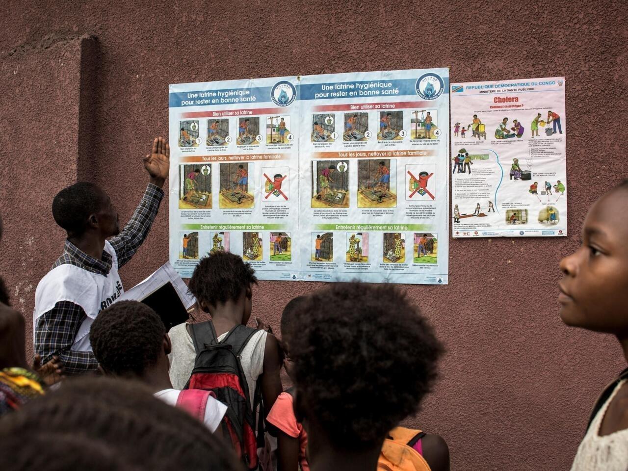 A member of the Congolese Red Cross explains the symptoms, risks and precautions of cholera to children in Kinshasa on January 18, 2018. The World Health Organization (WHO) on January 15 said there was a high risk of a cholera epidemic after flooding in Kinshasa, the teeming and ramshackle capital of the Democratic Republic of Congo. Beyond the capital, the latest cholera outbreak has affected 23 of the 26 provinces in the vast central African country since 2017, with « almost 50,000 cases and around 1,000 deaths », MSF estimates. Such figures make it the worst outbreak in DR Congo since 1994. / AFP PHOTO / JOHN WESSELS